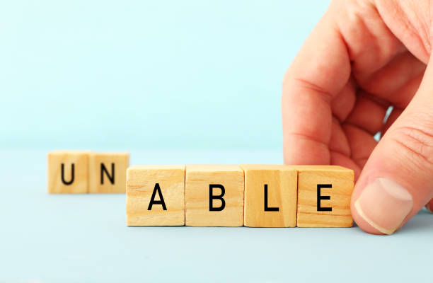 istock man hand spelling the text unable with wooden cubes, taking out the word un so it written able. success and challenge concept. 1090822540