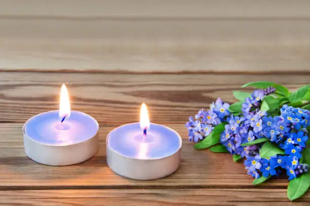 Flowers and two candles against wooden background