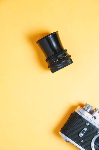 istock Old camera and lens on yellow background 1090827868