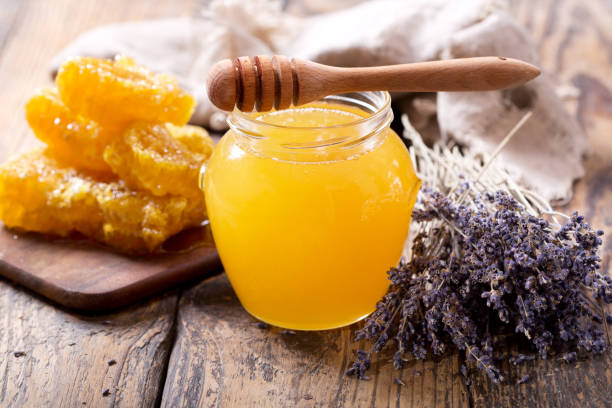 jar of lavender honey with dried lavender and honeycombs jar of lavender honey with dried lavender and honeycombs on wooden table honey jar liquid gourmet stock pictures, royalty-free photos & images