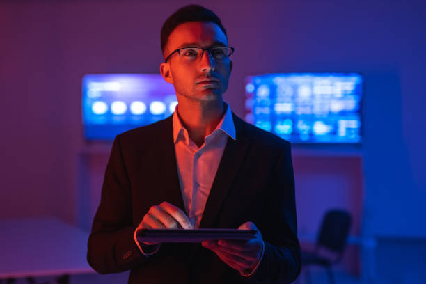 The businessman with a tablet working in a room with screens