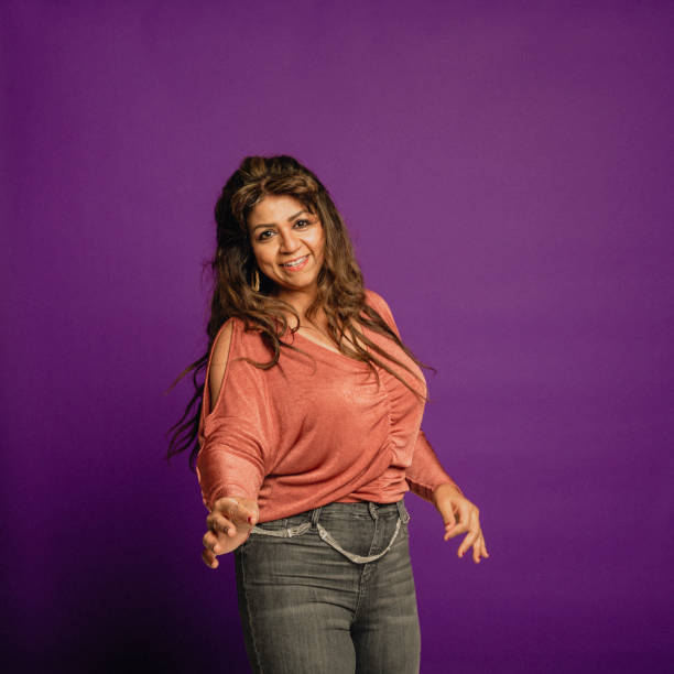 Mature Woman Dancing Portrait of a mature Asian woman dancing in front of a purple background. female salsa dancer stock pictures, royalty-free photos & images