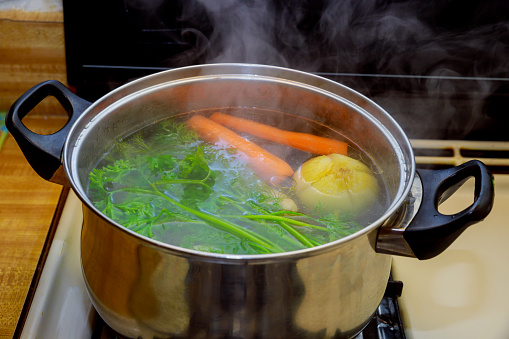 Close up broth in a pot vegetable ingredients for a soup boiling food