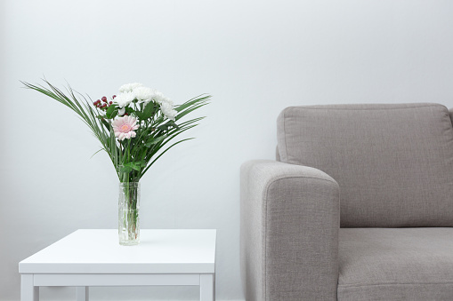 Couch next to table of flowers modern living room decor against white background
