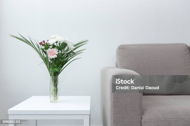 Couch Next To Table Of Flowers Modern Living Room Decor Against White Background Stock Photo - Download Image Now