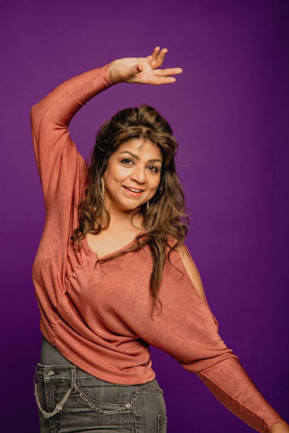 Portrait of a Mature Woman Dancing Portrait of a mature Asian woman dancing in front of a purple background. female salsa dancer stock pictures, royalty-free photos & images