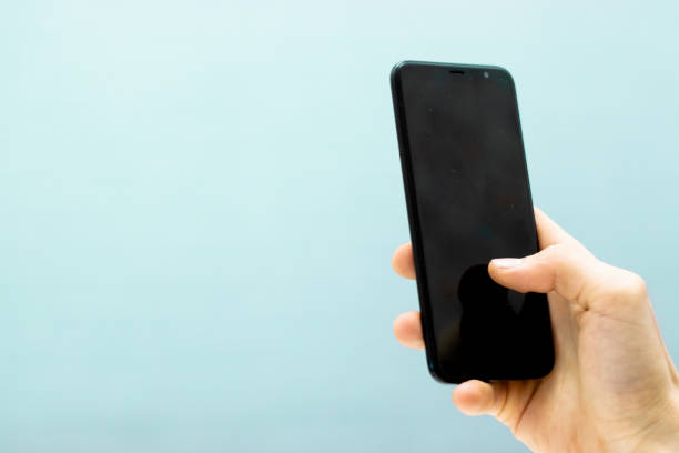 istock Hand holding smartphone mobile and touching screen isolated on blue background 1090860904