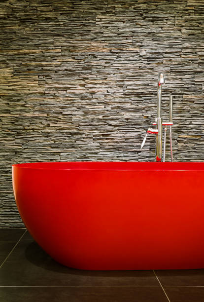modern red bathtub with natural stone wall stock photo