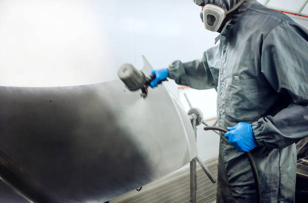 Car mechanic spraying paint on car hood stock photo