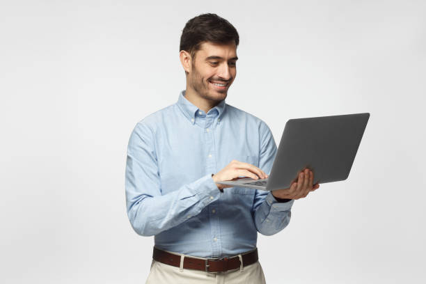 istock Young handsome business man standing, holding laptop with happy smile, typing, using touchpad 1090878436