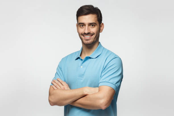 retrato de uma jovem atraente desportivo em camisa polo azul em pé com os braços cruzados, isolado no fundo cinza - blue polo shirt - fotografias e filmes do acervo