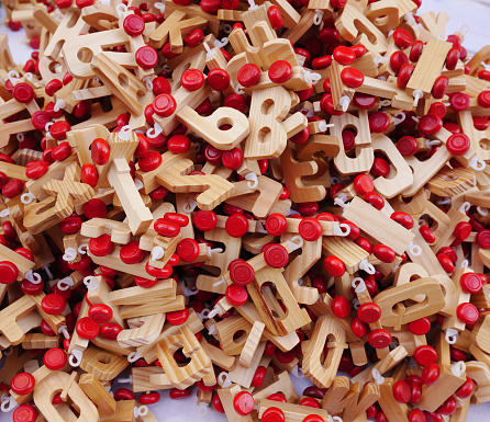 A mountain of handmade wooden letters with red wheels as a base. Horizontal view