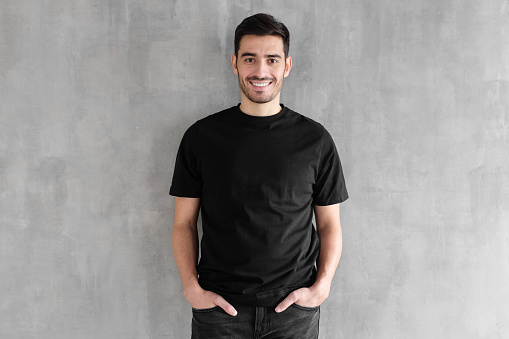 Mock up of young man body in empty black t-shirt isolated on textured gray wall background