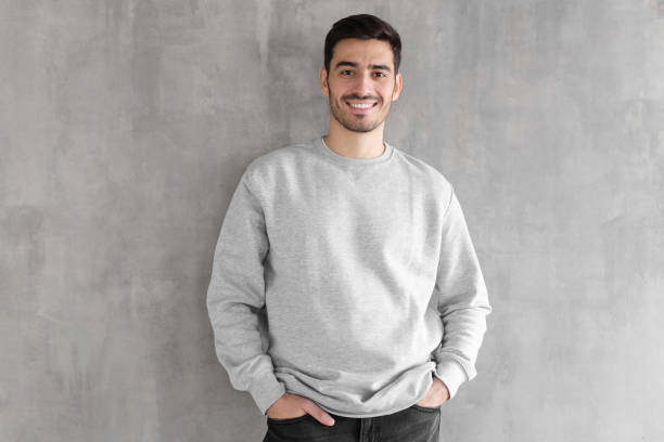 young man in oversized sweatshirt isolated on textured gray wall background - sweatshirt imagens e fotografias de stock