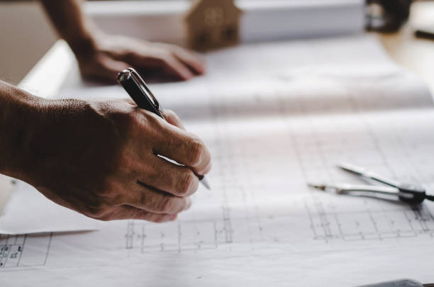 istock close up of hand professional architect, engineer or interior reviewing blueprint on workplace desk in office center at construction site, contractor, construction, engineering and business concept 1090894302