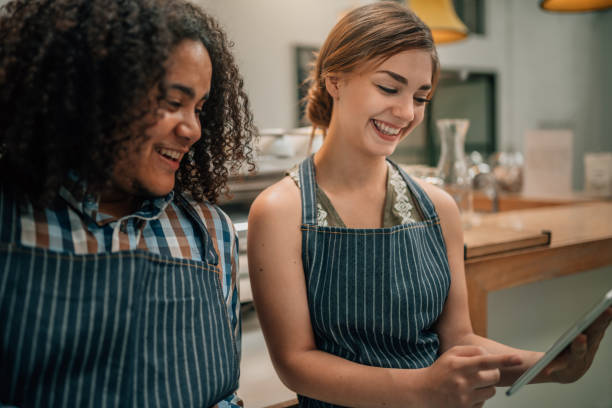 istock Two waiters smiling and laughing at something being pointed to on a digital tablet 1090912632