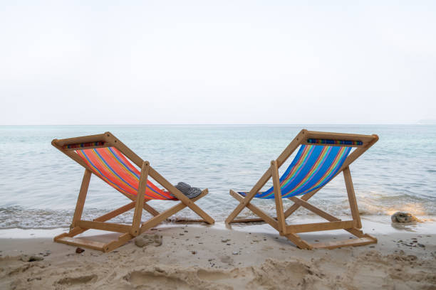 The orange and blue beach chair are on the clear sand beach with sea in background stock photo