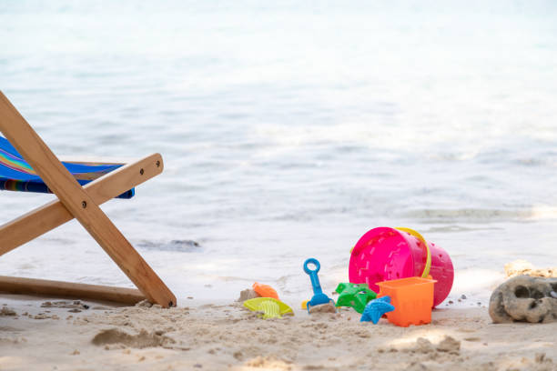 The blue beach chair and sand toy boxes are on the beach with sea in background stock photo