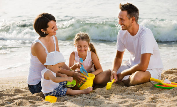 istock Parents with two kids playing with toys on beach 1090915822