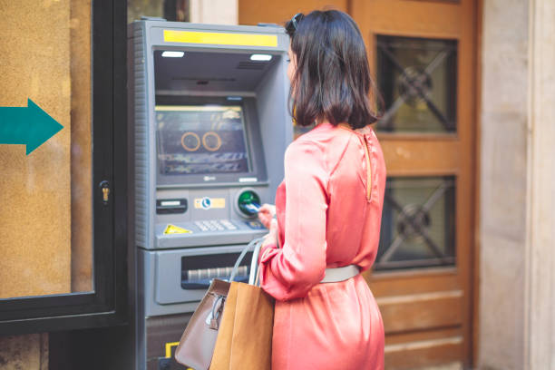 Young woman is withdrawing cash from an atm machine