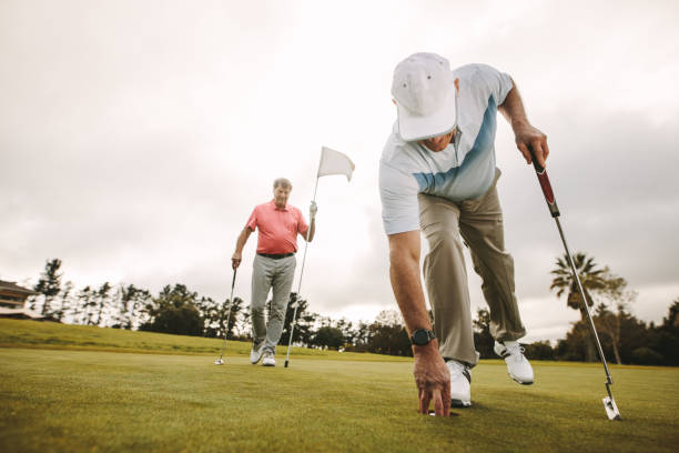 Golfer picking golf ball out of hole