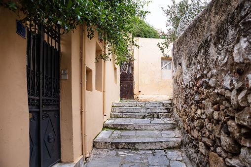 Plaka, Athens Greece. Old town narrow pedestrian streets and stairs, houses facades and stone walls. Low angle, perspective view