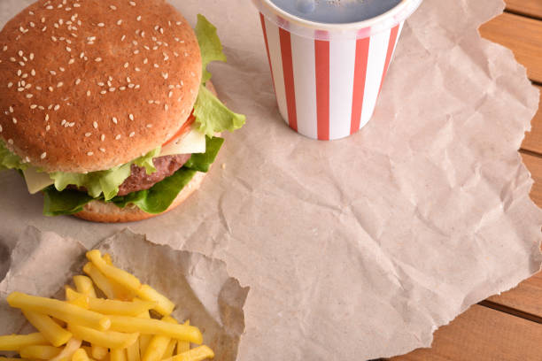 istock Burger with soda and chips on paper close up top 1090941120