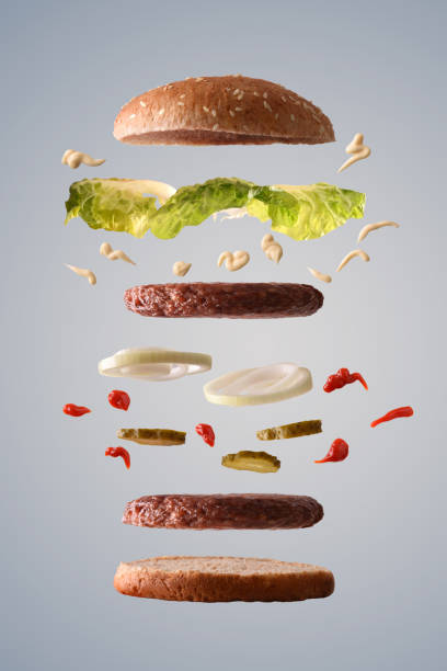 istock Double hamburger floating with lettuce onion and pickles gray background 1090941208