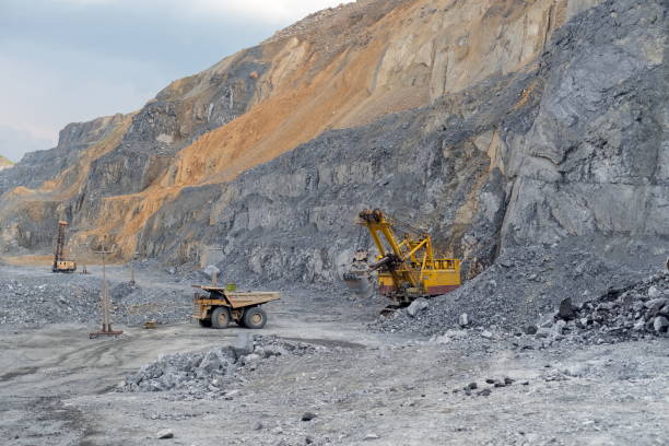 il camion di scarico caterpillar carico di minerale di nefelina si allontana dall'escavatore. - caterpillar truck foto e immagini stock