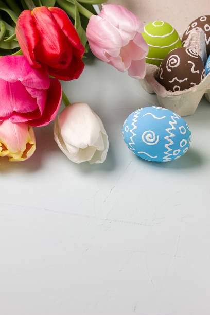 istock Painted easter eggs and bouquet of spring tulips closeup on a light blue background with space for congratulation 1090944168