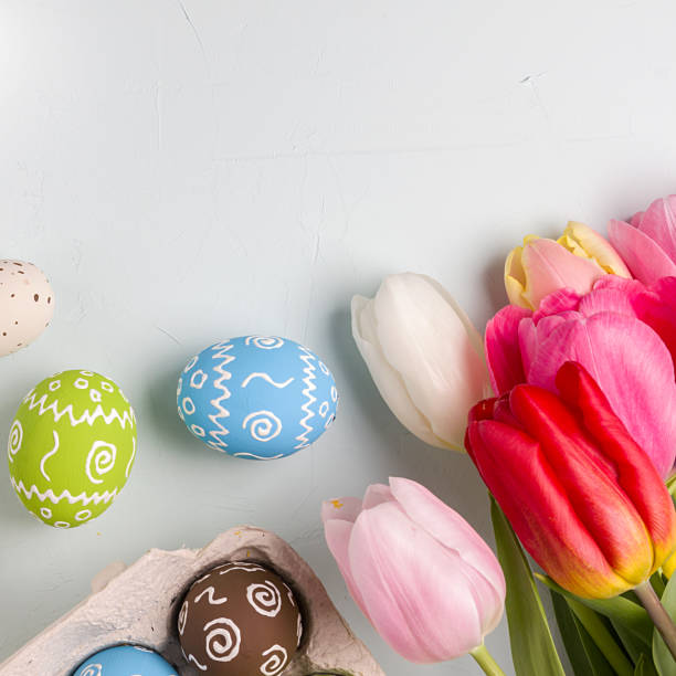 istock Painted easter eggs and bouquet of spring tulips closeup on a light blue background with space for congratulation 1090944196