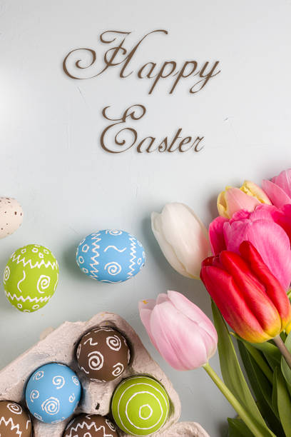 istock Painted easter eggs and bouquet of spring tulips closeup on a light blue background with space for congratulation 1090944204
