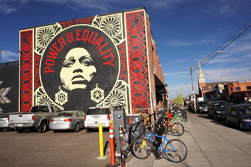 Denver, Colorado, USA - 21 December 2018: View of the mural on the sunny end wall of Denver Central Market on Larimar St at 27th, which is now a popular food court with several small food stalls. The mural overlooks a parking lot. A sidewalk  bicycle rack is in the foreground.