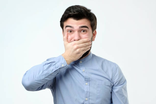 istock Good looking young man covering mouth with hand and looking at camera 1090945218