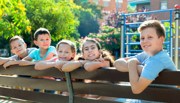istock Five children sitting on a bench at the playground 1090945414
