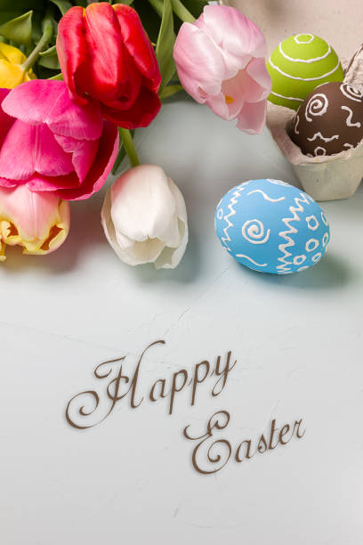istock Painted easter eggs and bouquet of spring tulips closeup on a light blue background with space for congratulation 1090947836