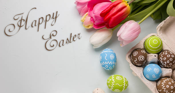 istock Painted easter eggs and bouquet of spring tulips closeup on a light blue background with space for congratulation 1090947860