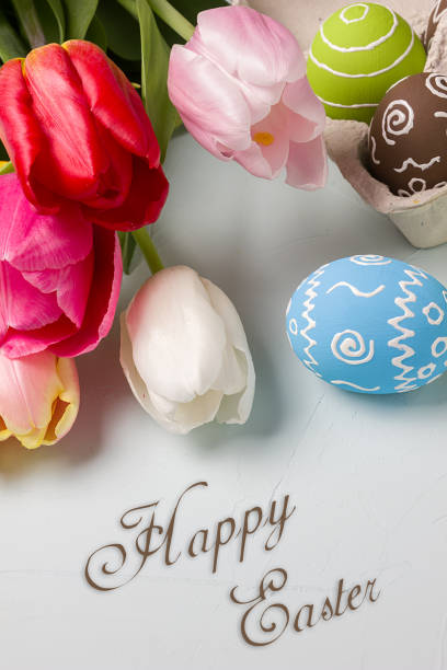 istock Painted easter eggs and bouquet of spring tulips closeup on a light blue background with space for congratulation 1090947866