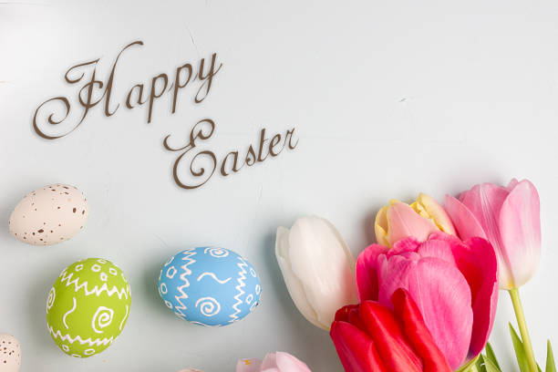 istock Painted easter eggs and bouquet of spring tulips closeup on a light blue background with space for congratulation 1090947896