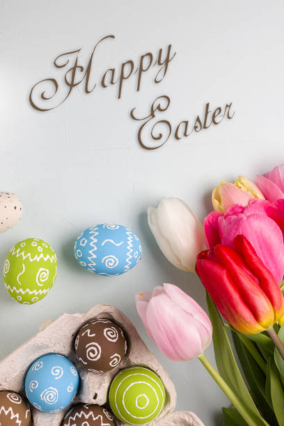 istock Painted easter eggs and bouquet of spring tulips closeup on a light blue background with space for congratulation 1090947918