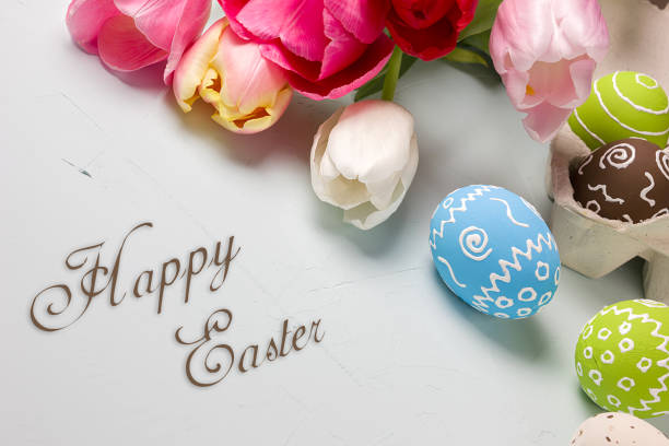 istock Painted easter eggs and bouquet of spring tulips closeup on a light blue background with space for congratulation 1090947958