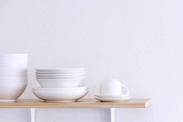 istock Wooden shelf template isolated on white wall background which on set stacked white bowls and plates as items tableware for decorated interior or montage of your product on shelf with copy space. 1090949036