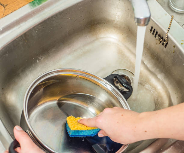 istock Woman wastes water while washing dishes 1090951166
