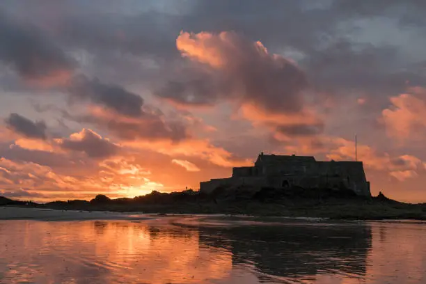 Sunset on the beach and Fort National during low tide in Saint Malo (Bretagne, France) on a cloudy day in summer