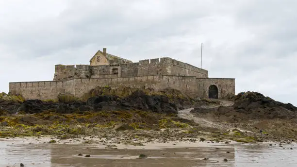 The beach and Fort National during low tide in Saint Malo (Bretagne, France) on a cloudy day in summer