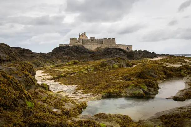 The beach and Fort National during low tide in Saint Malo (Bretagne, France) on a cloudy day in summer