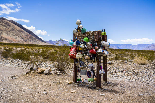 Teakettle Junction, Death Valley May 27, 2018 Death Valley / CA / USA - Teakettle Junction sign covered in tea kettles left by visitors teakettle junction stock pictures, royalty-free photos & images