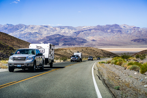 May 28, 2018 Death Valley / CA / USA - Pick up trucks with RV travel trailers driving though Death Valley National Park; Panamint Valley visible in the background