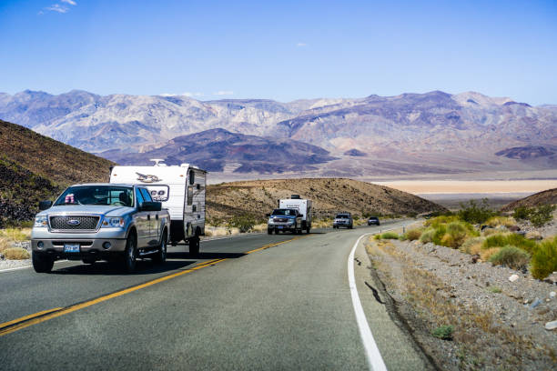 Pick up trucks with RV travelling through Death Valley May 28, 2018 Death Valley / CA / USA - Pick up trucks with RV travel trailers driving though Death Valley National Park; Panamint Valley visible in the background death valley desert photos stock pictures, royalty-free photos & images