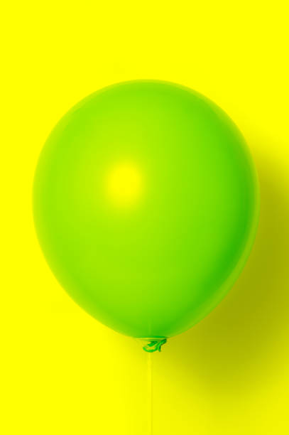 istock Green balloon on yellow background with shadow. Side glare. 1090979752